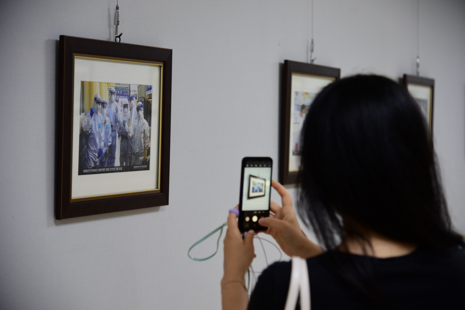 2. 계명대학교 대구동산병원에서 코로나19와 벌인 115일간의 사투라는 제목의 코로나19 극복 희망 사진전에서 한 시민이 의료진의 모습을 핸드폰에 담고 있다.JPG 관련이미지 2